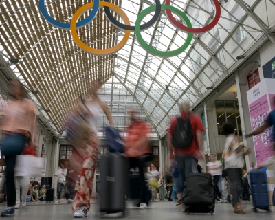 Commuters walk under the Olympic rings at the Gare de Lyon train station, on July 23, 2024, ahead of the Paris 2024 Olympic and Paralympic Games.