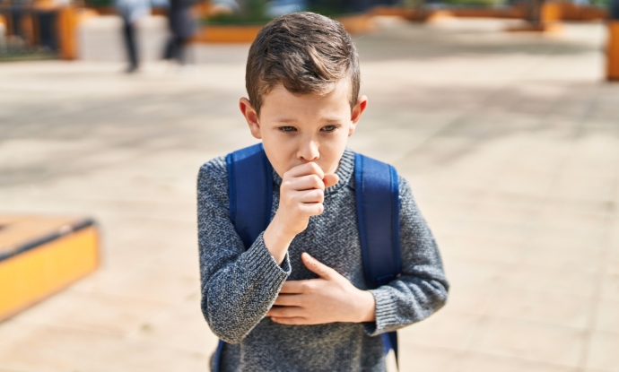 child coughing into hand outside school